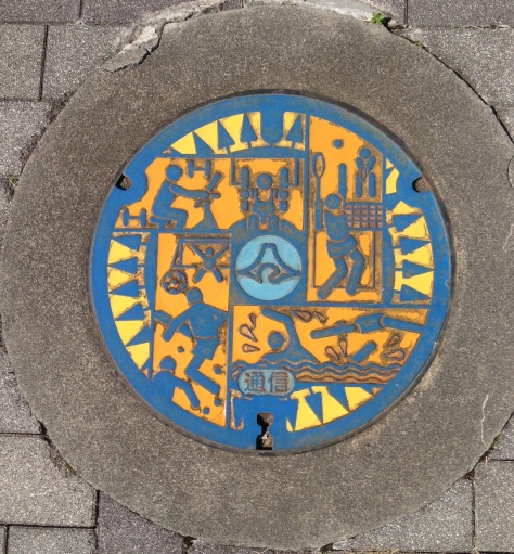 A manhole cover design showing various sports at Elope Stadium in Shizuoka Prefecture.